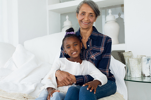 Portrait close up of African-American girl and mixed race grandmother sitting on bed. Authentic Senior Retired Life Concept