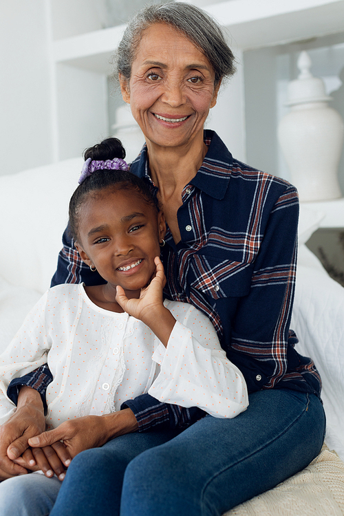 Portrait close up of African-American girl and mixed race grandmother sitting on bed. Authentic Senior Retired Life Concept