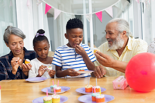 Front view of African-American family eating cupcakes. Authentic Senior Retired Life Concept