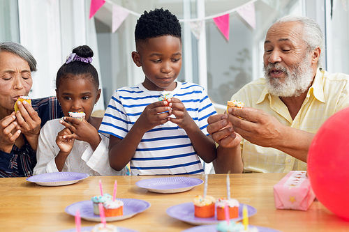 Front view of African-American family eating cupcakes. Authentic Senior Retired Life Concept