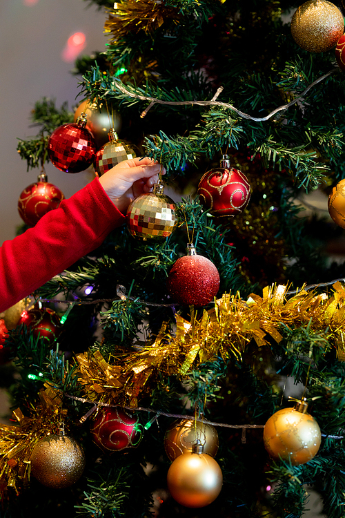 Hand of a young Caucasian girl decorating the Christmas tree in the sitting room at Christmas time