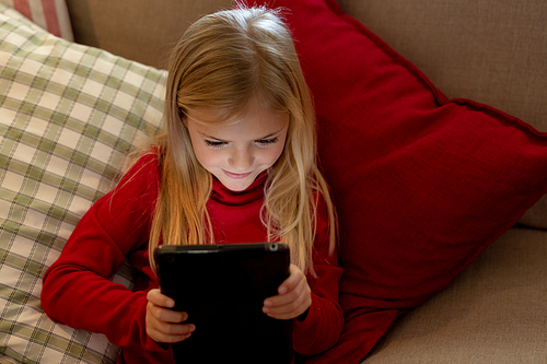 Front view of a young Caucasian girl using a tablet in the sitting room