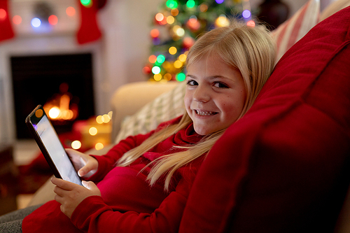 Portrait of a young Caucasian girl using a tablet in the sitting room at Christmas time