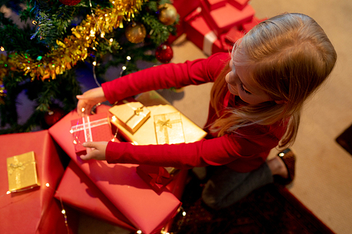Overhead view of a young Caucasian girl wrapping presents in her sitting room at Christmas time