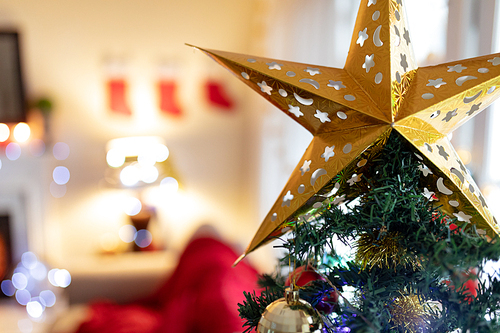 Close up of a gold star on top of a Christmas tree at Christmas time at home