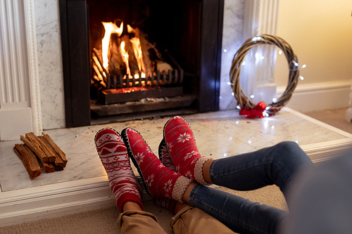 Legs of a mixed race couple in their sitting room at Christmas, lying on the floor by a fireplace
