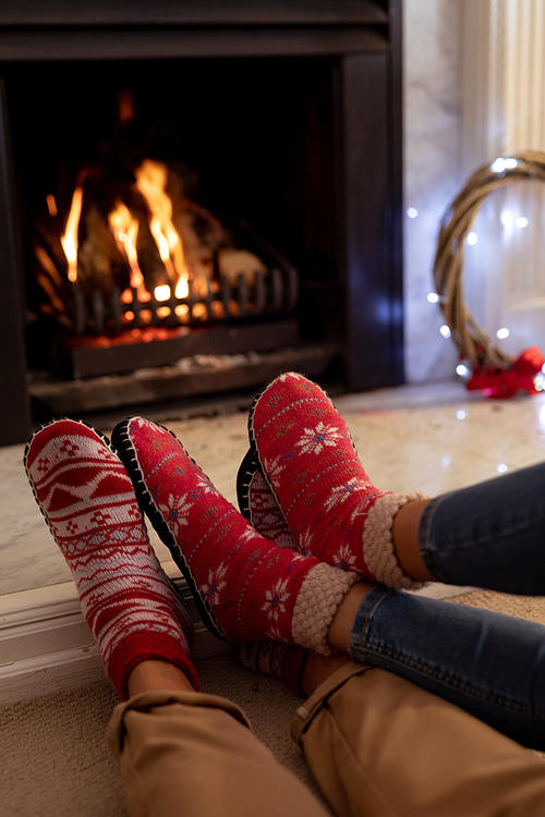 Close up of legs of a mixed race couple in their sitting room at Christmas, lying on the floor by a fireplace