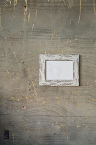 Close up of a framed blank picture hanging on a concrete wall