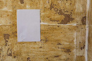 Close up of a blank sign hanging on a distressed wall