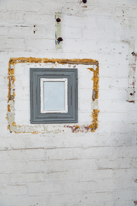 Close up of a framed blank picture hanging on a white brick wall