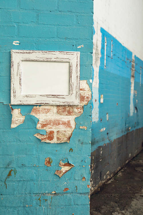 Close up of a framed blank picture hanging on a distressed wall