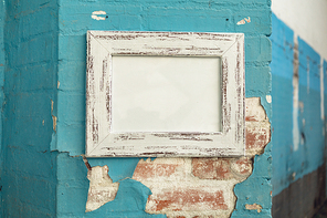 Close up of a framed blank picture hanging on a distressed wall