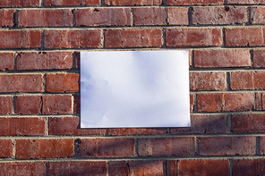 Close up of a blank sign hanging on a red brick wall