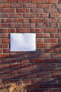 Close up of a blank sign hanging on a red brick wall