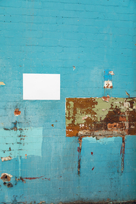 Close up of a blank sign hanging on a blue brick wall