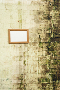 Close up of a framed blank picture hanging on a stained brick wall