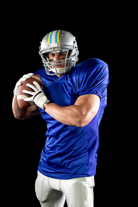 Front view of a Caucasian male American football player wearing a team uniform, pads and a helmet, with eye black under his eyes, preparing to throw the ball. Vertical shot