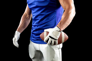 Side view mid section of a Caucasian male American football player wearing a team uniform, pads and gloves holding a football in one hand