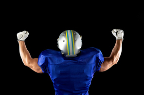 Rear view of a Caucasian male American football player wearing a team uniform, pads and a helmet, raising arms in triumph