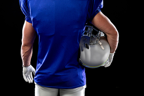 Rear view mid section of a Caucasian male American football player wearing a team uniform, pads and gloves, holding a helmet under his arm