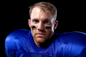 Portrait close up of a Caucasian male American football player wearing a team uniform with shoulder pads and lines of eye black under his eyes