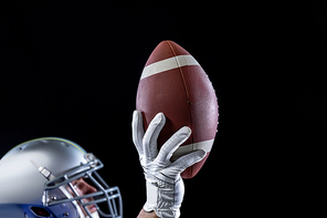 Side view of a Caucasian male American football playing wearing a helmet looking up and holding a football in one gloved hand