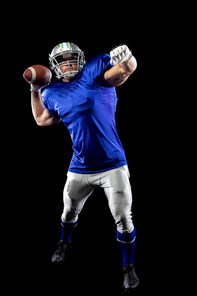 Front view of a Caucasian male American football player wearing a team uniform, pads and a helmet, about to throw a football