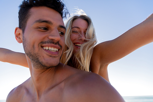 Caucasian couple enjoying time at the beach, a man is holding a woman piggy back