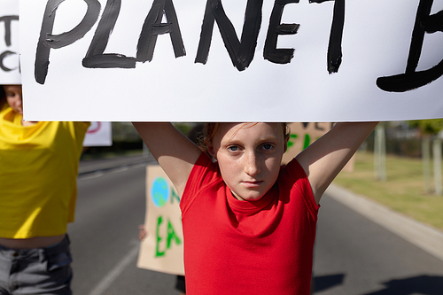 Portrait of a Caucasian girl on a protest march with her elementary school classmates, carrying signs with environmental and conservation slogans on them