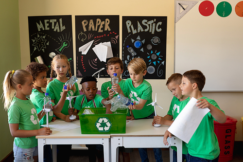 Diverse elementary school being socially concious. Group of schoolchildren wearing green t shirts with a white recycling logo on them