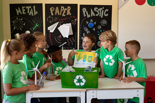 Diverse elementary school being socially concious. Group of schoolchildren wearing green t shirts with a white recycling logo on them