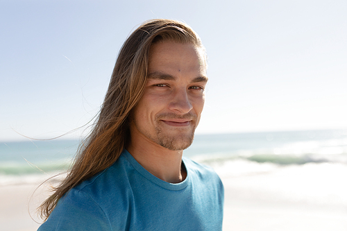 Portrait of a Caucasian man enjoying his time at the beach with his friends on a sunny day, looking at the camera and smiling