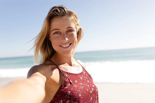 Portrait of a Caucasian woman enjoying her time at the beach with her friends on a sunny day, looking at the camera and smiling