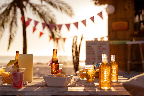 Beverages and food are lying on a tablre with a surfing lessons hut standing in the background with a palm tree on a sunny day