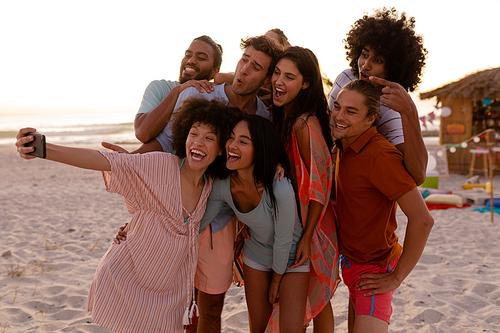 A multi-ethnic group of friends enjoying their time together, holding a smartphone, taking a selfie together