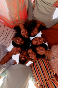 A multi-ethnic group of friends enjoying their time together, standing in a row, embracing each other, looking at the camera, making a huddle