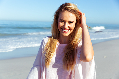Portrait of a Caucasian woman enjoying time at the beach on a sunny day,  and smiling, with sea in the background