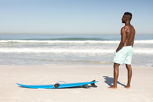 A happy, attractive African American man enjoying free time on beach on a sunny day, smiling, having fun, surfing, sun shining on his face.