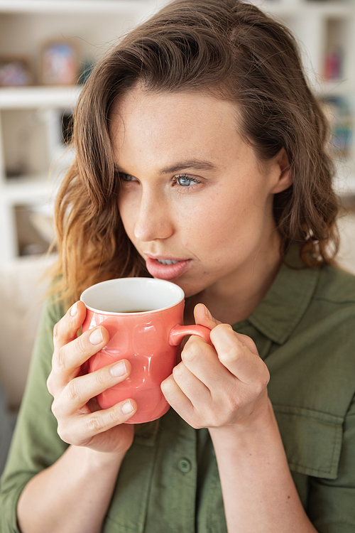 Caucasian woman spending time at home, sitting on sofa, drinking coffee from a mug. Lifestyle at home isolating, social distancing in quarantine lockdown during coronavirus covid 19 pandemic.