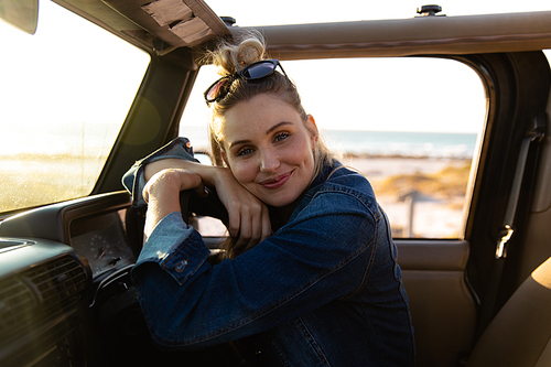 Front view close up of a Caucasian woman inside an open top car, holding a steering wheel and smiling to camera