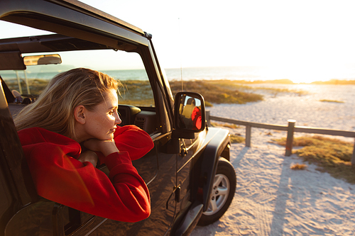 Side view of a Caucasian woman inside an open top car, looking through the window. Weekend beach vacation, lifestyle and leisure.