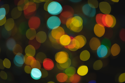 Multiple multi coloured blue, orange, red out of focus spots of light fairy lights on black background. Colour, Christmas and celebration concept.