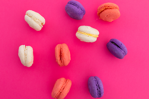High angle view of purple, pink and white macarons on pink background. fresh dessert fun food concept.