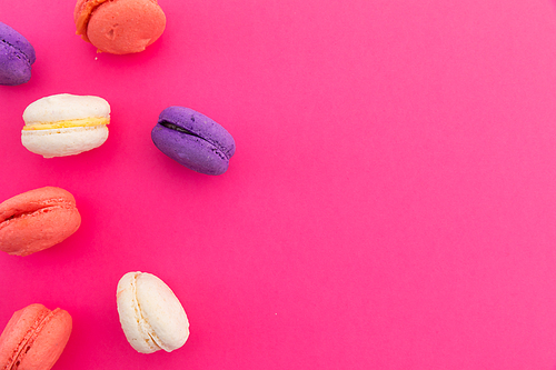 High angle view of purple, pink and white macarons on pink background. fresh dessert fun food copy space concept.