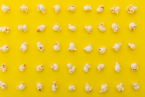 High angle view of popcorn in multiple rows on yellow background. fun party food sweet treat snack concept.