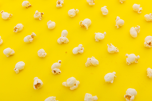 High angle view of popcorn in multiple rows on yellow background. fun party food sweet treat snack concept.