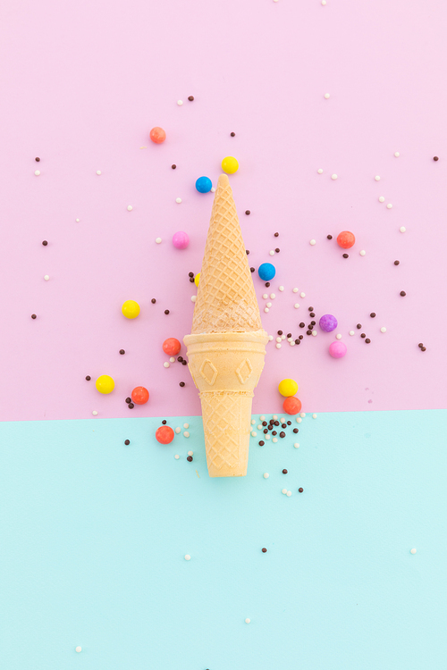Two ice cream cones and scattered colourful sprinkle on pink and blue background. fresh dessert fun food copy space concept.