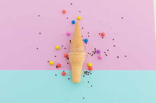 Two ice cream cones and scattered colourful sprinkle on pink and blue background. fresh dessert fun food copy space concept.
