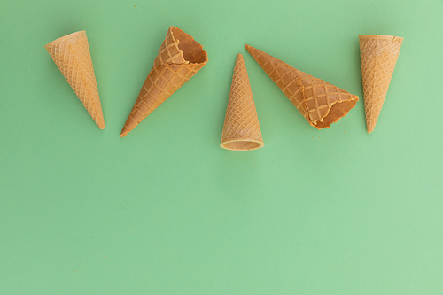 High angle view of five ice cream cones on green background. fresh dessert fun food copy space concept.
