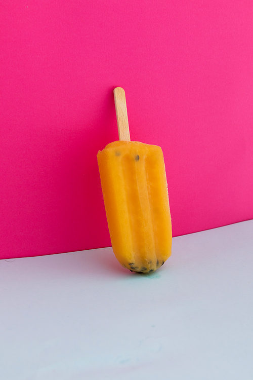 Close up of yellow ice lollipop upside down on pink background. food dessert summer fun concept.